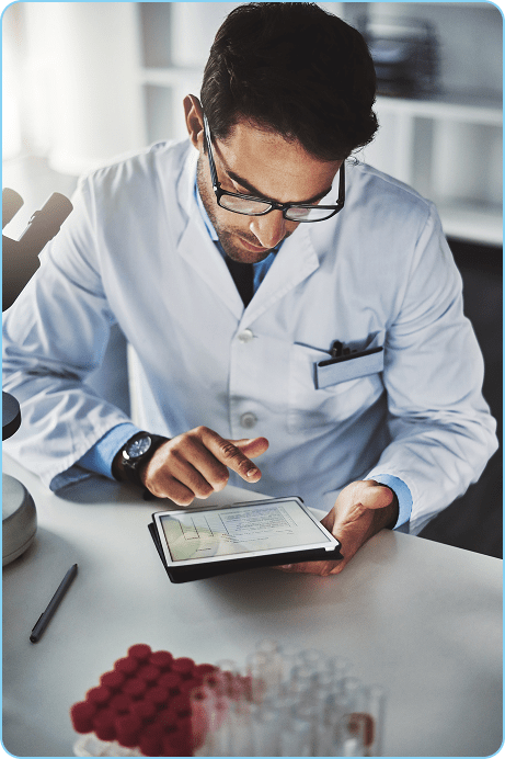 scientist-using-tablet-at-desk-with-microscope